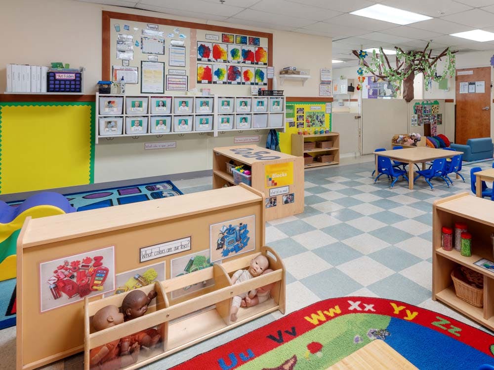 Classroom with children's artwork, cubbies, tables, chairs, and toys