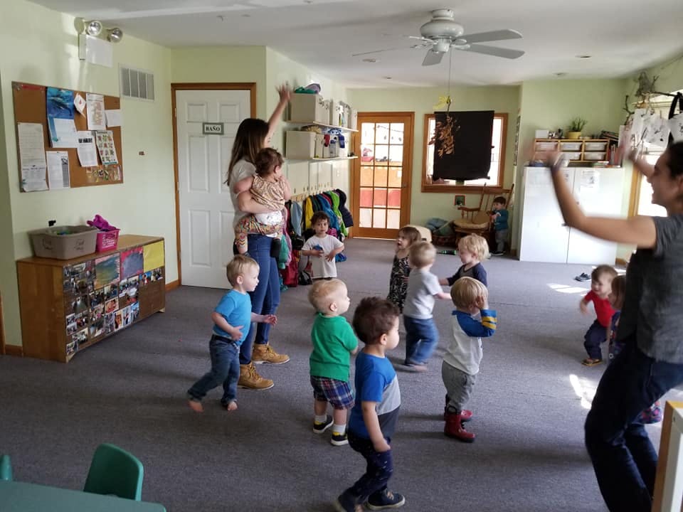Adults and children in a room, some with arms raised