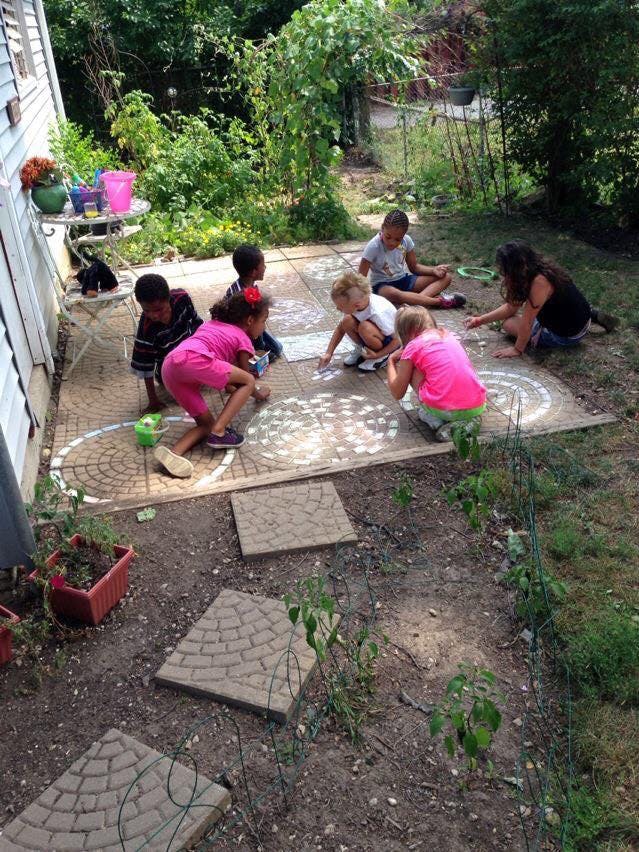 Adult and children drawing with chalk on a patio
