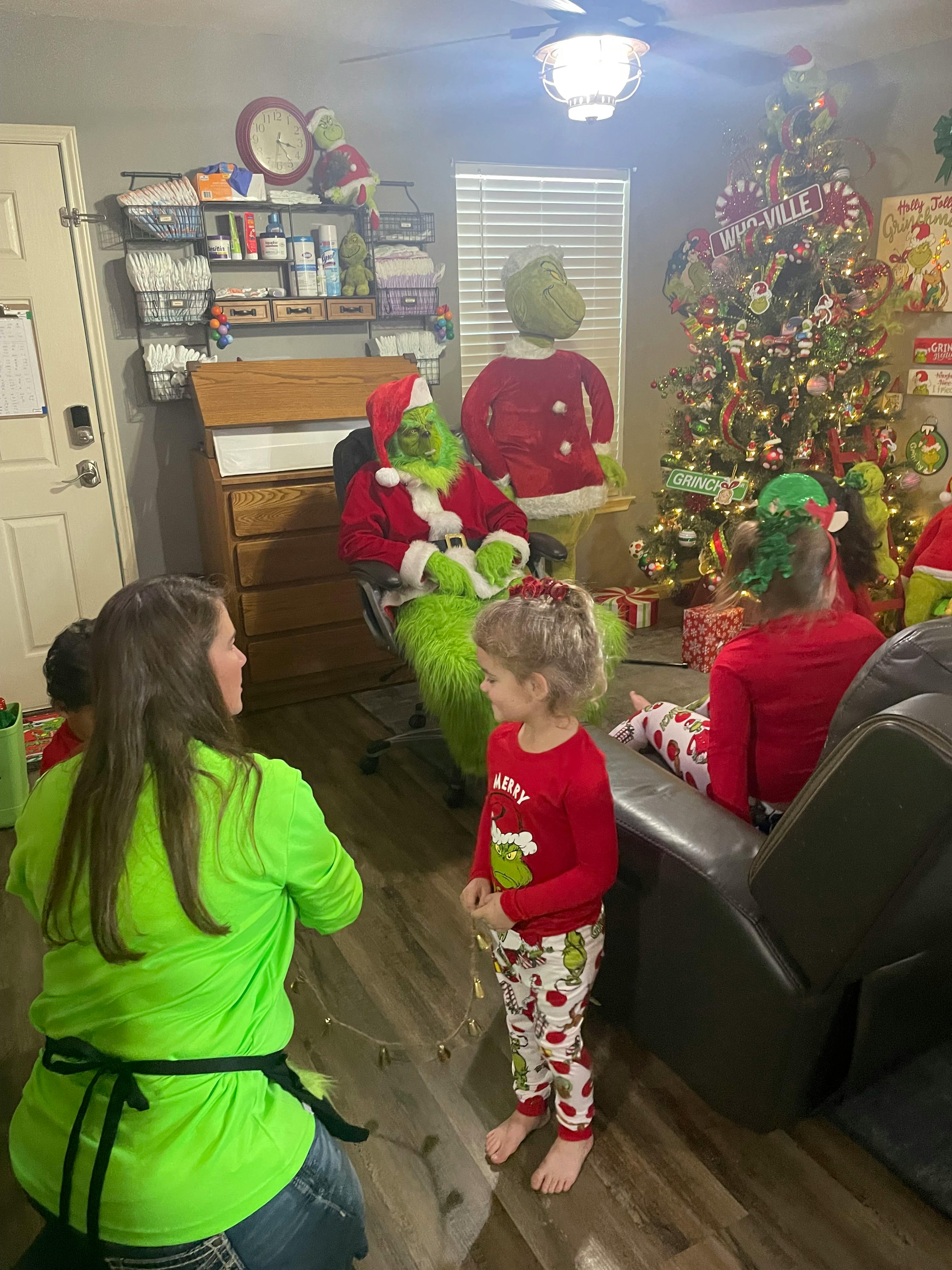 People and children in a room with a person dressed as the Grinch