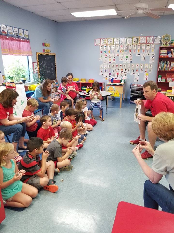Adults and children sitting on the floor in a classroom