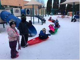 Children sledding in the snow on a playground