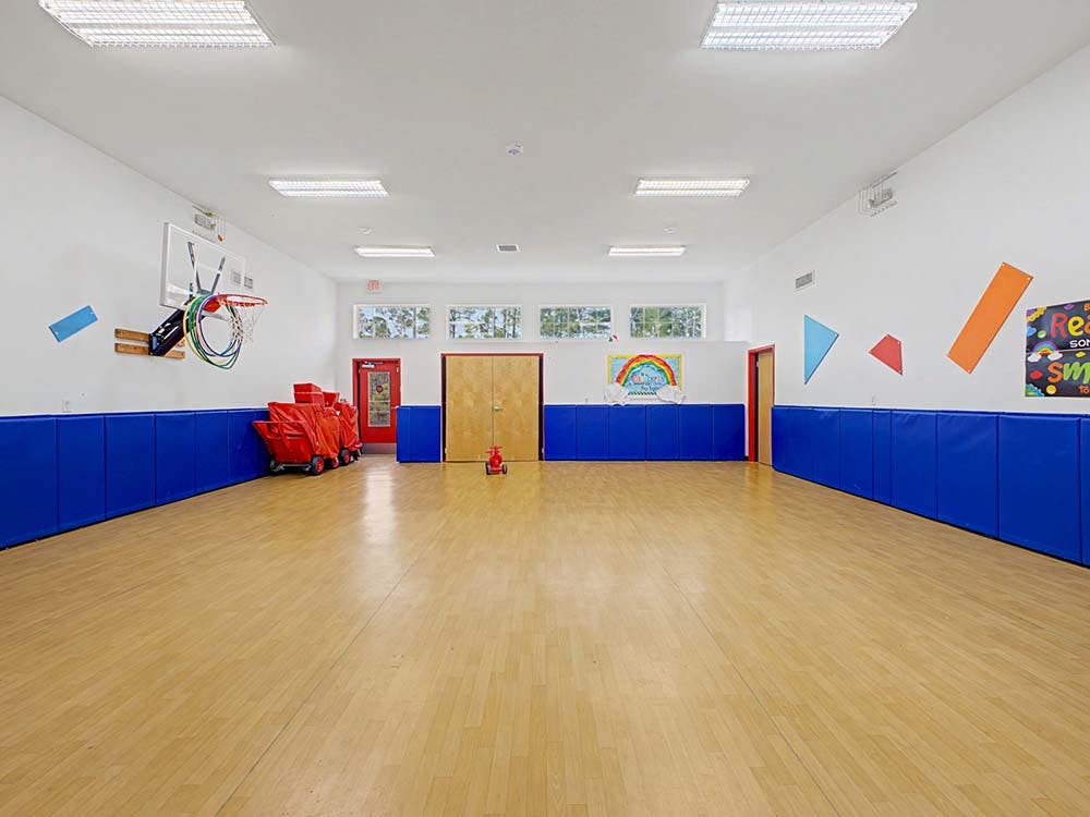Empty gym room with a basketball hoop and padded blue walls