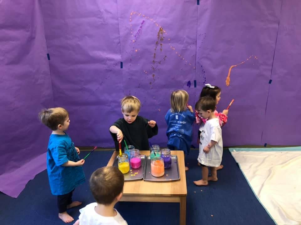 Children painting on a purple wall