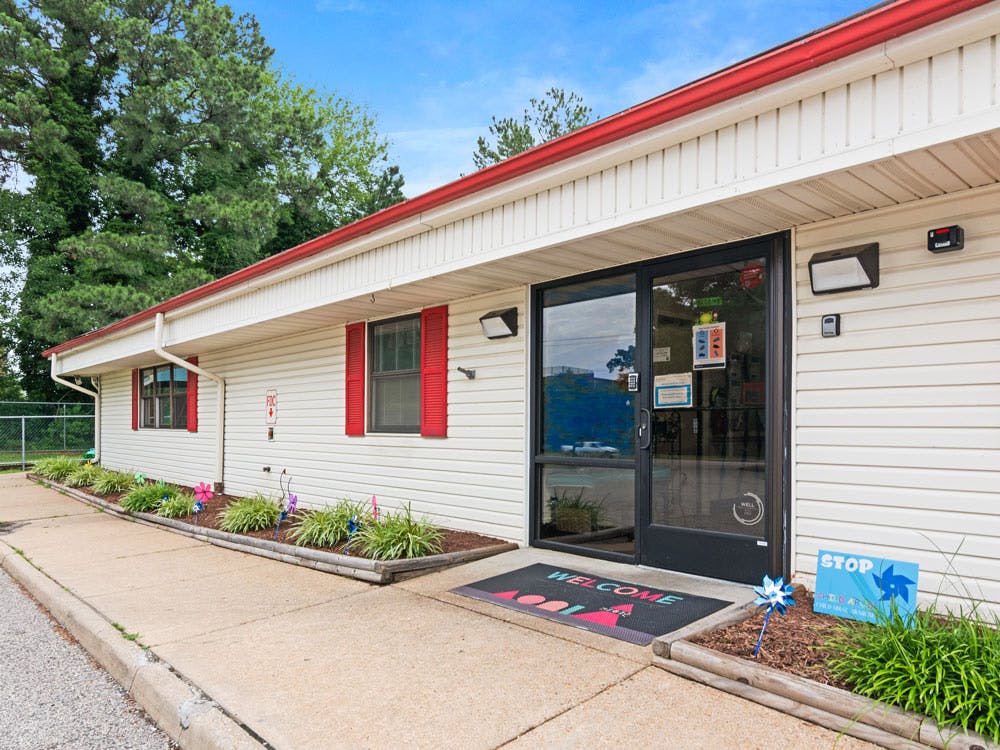 Entrance to a white building with red window shutters and a black door