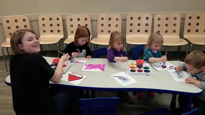 Person and children painting at a table