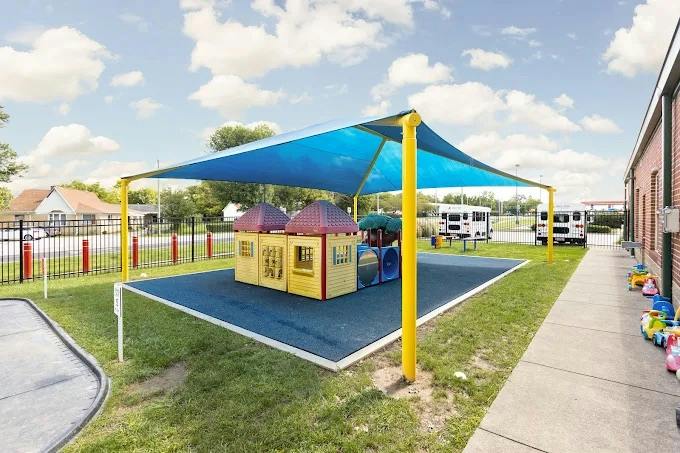 A covered outdoor play area with a small playhouse and a blue shade canopy