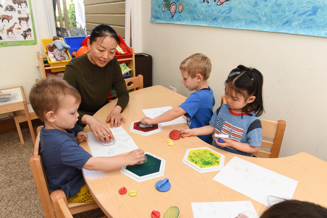 Adult and three children at a table with art supplies