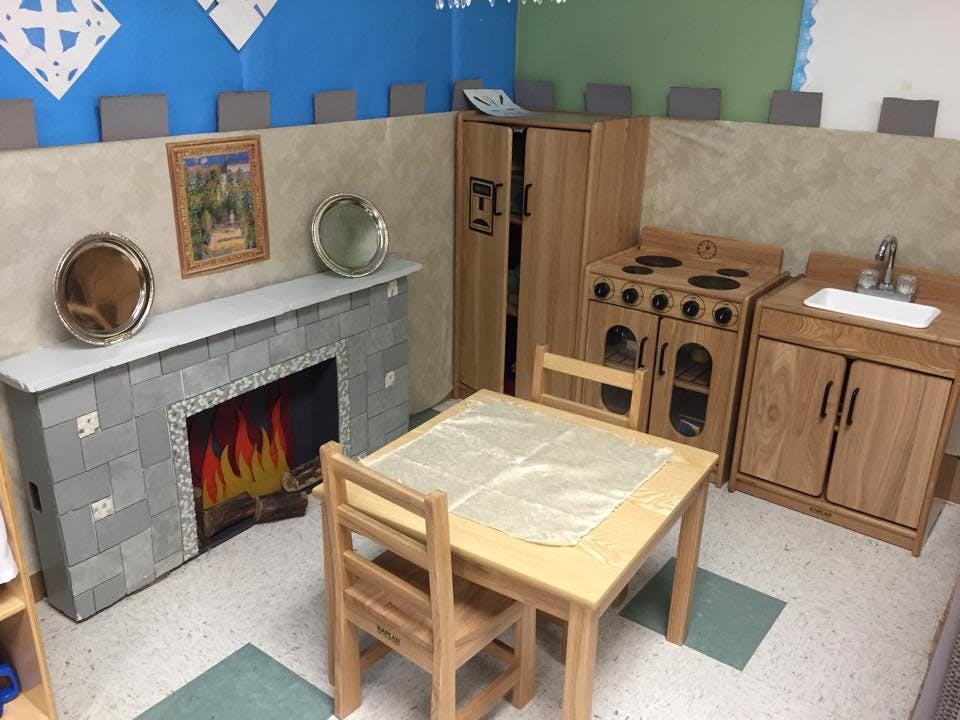 Playroom with toy kitchen, table and chairs, and faux fireplace