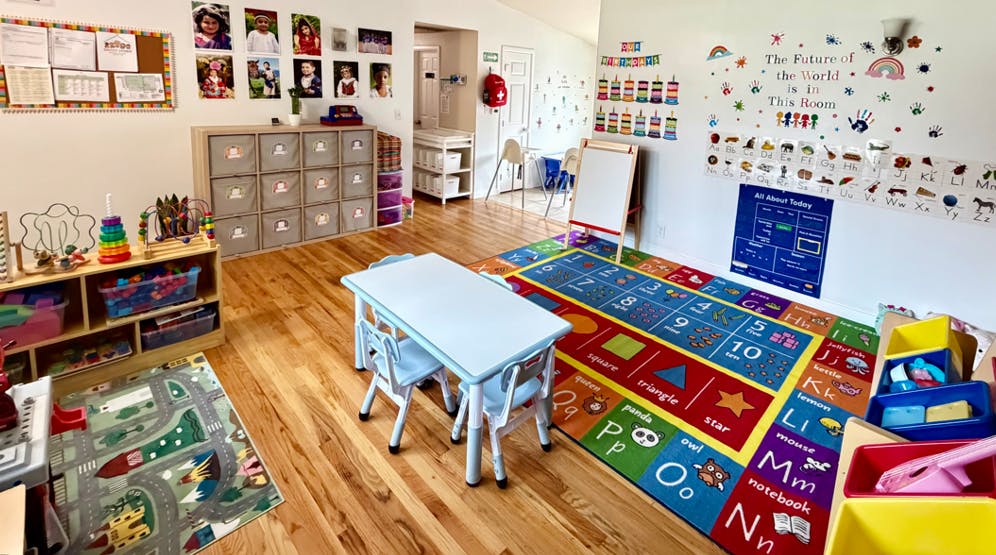 brightly decorated classroom with tables, chairs, toys, and educational posters