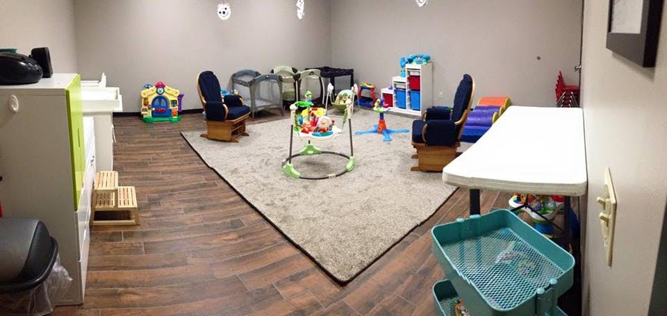 Room with a rug, two rocking chairs, and various baby and child play items