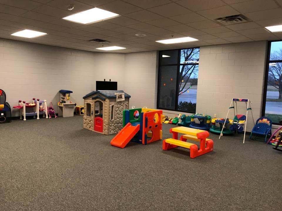 Indoor play area with a playhouse, slide, and small picnic table