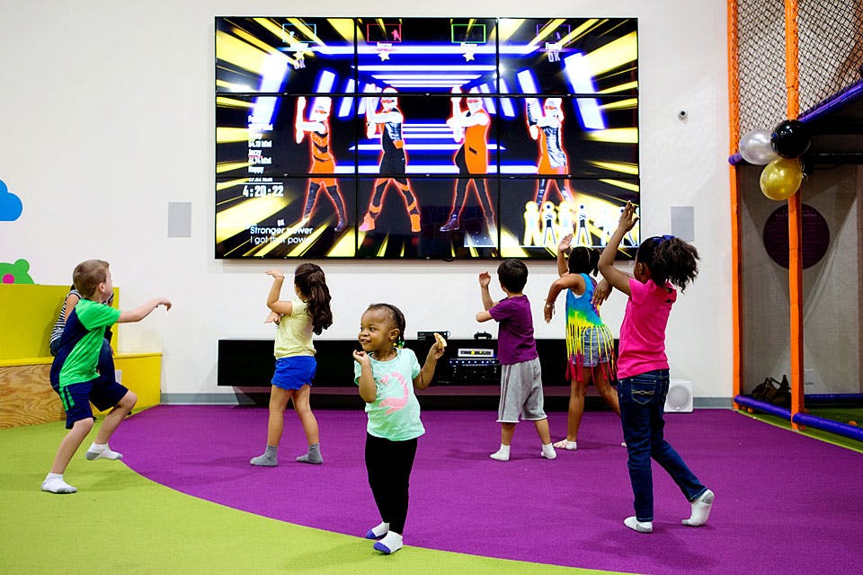 Children dancing in front of a large screen showing animated dancers