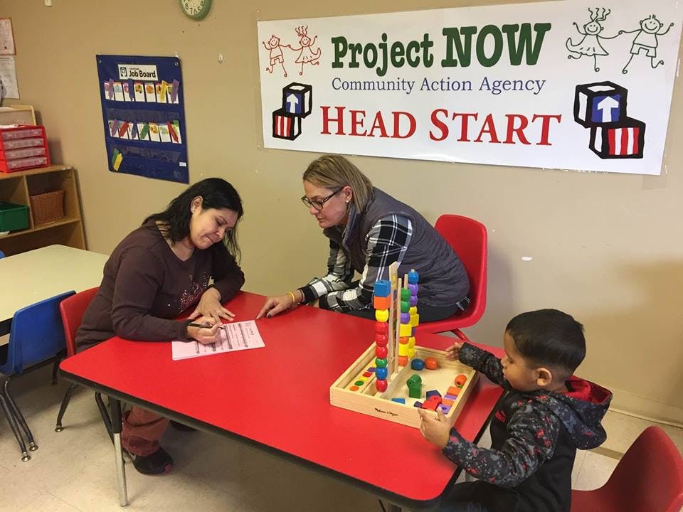 Two people and a child at a red table, child playing with a toy