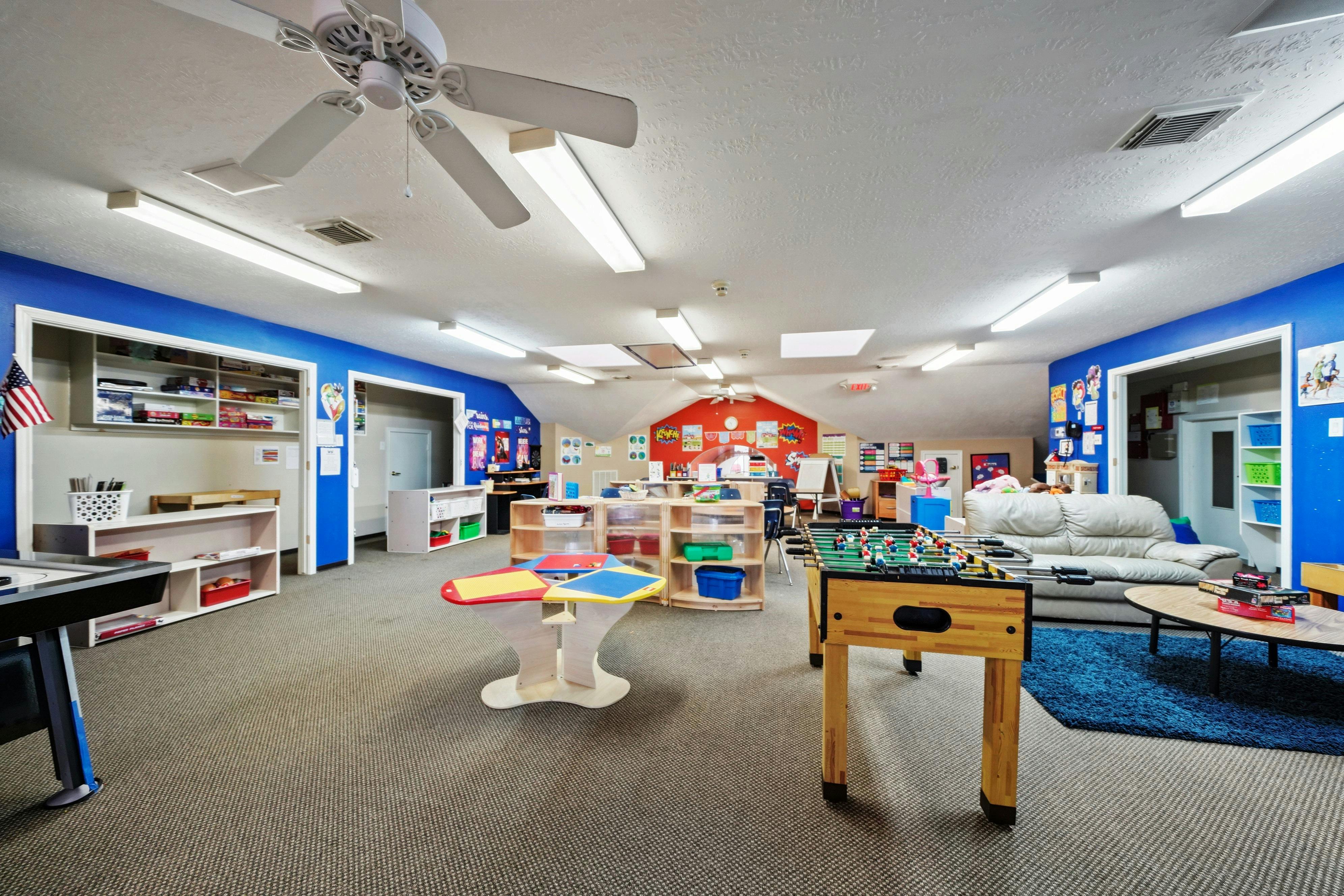 Playroom with blue walls, foosball table, and various toys and furniture