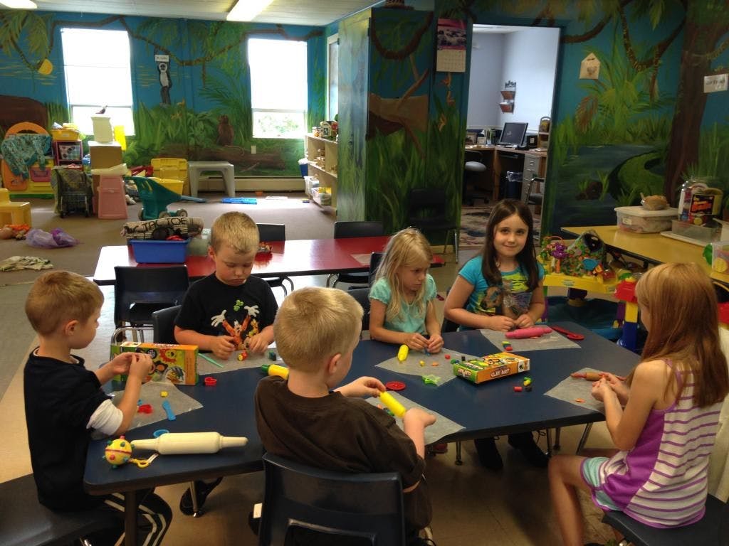 Children sitting at a table playing with modeling clay