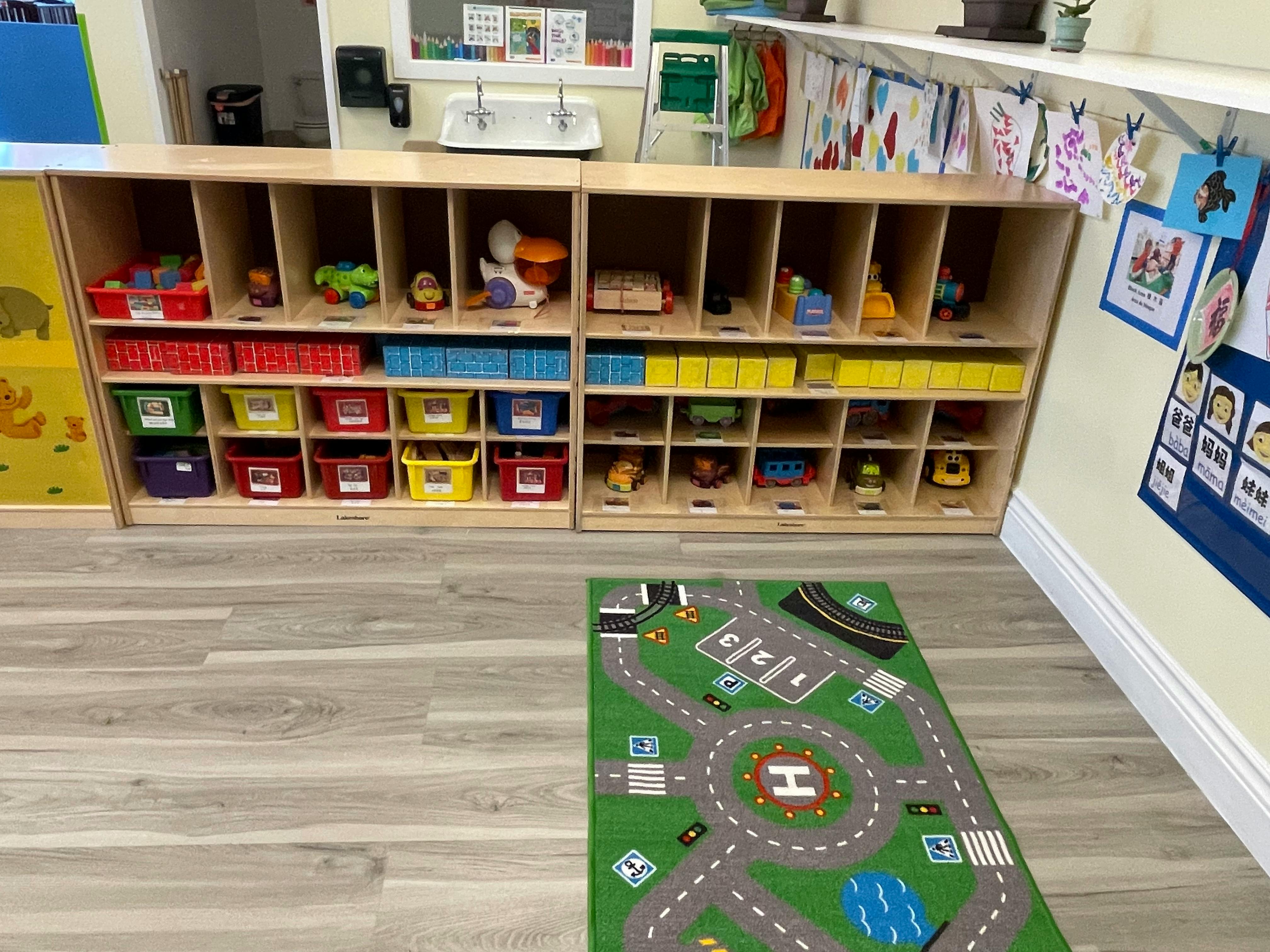 Classroom with cubbies full of toys and a road map rug