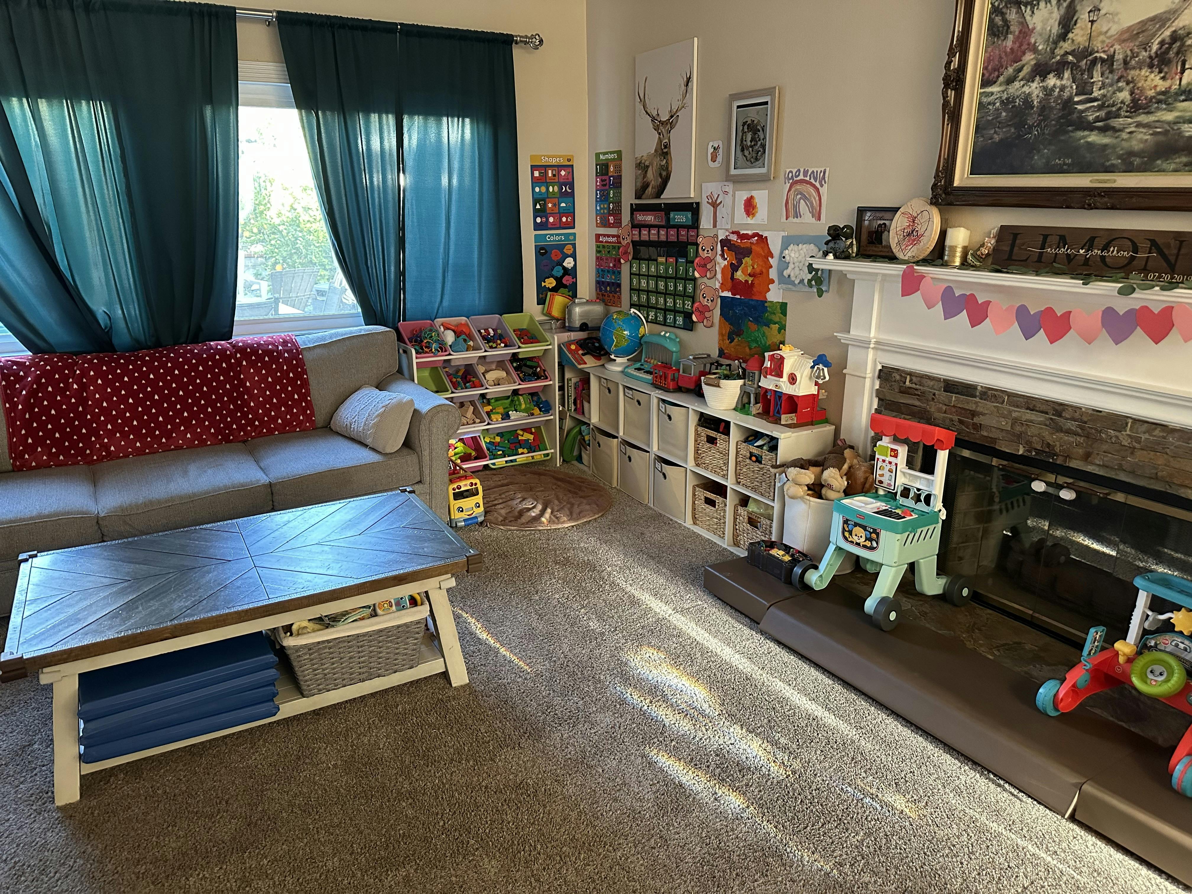 Living room with a gray couch, coffee table, and children's toys near a fireplace