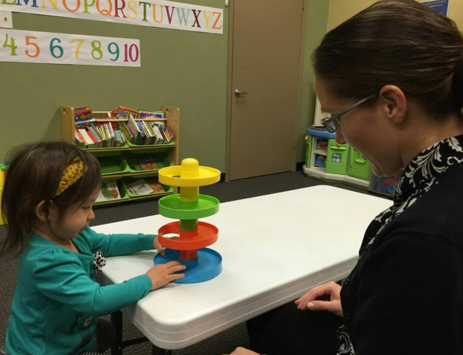 Adult and child playing with a colorful toy on a white table
