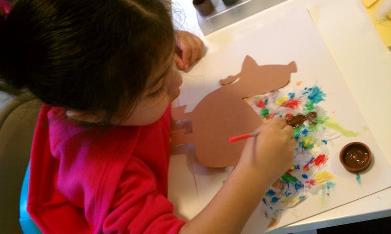 Child painting a cutout shape