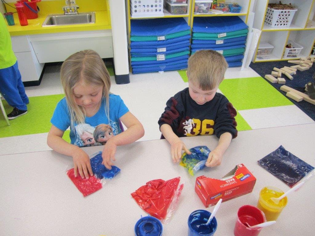 Two children playing with colorful sensory bags at a table
