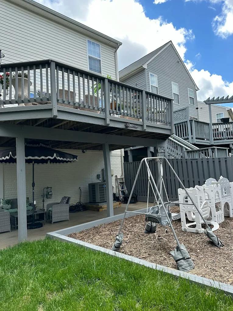Backyard patio with a wooden deck and a playground area featuring a swing set