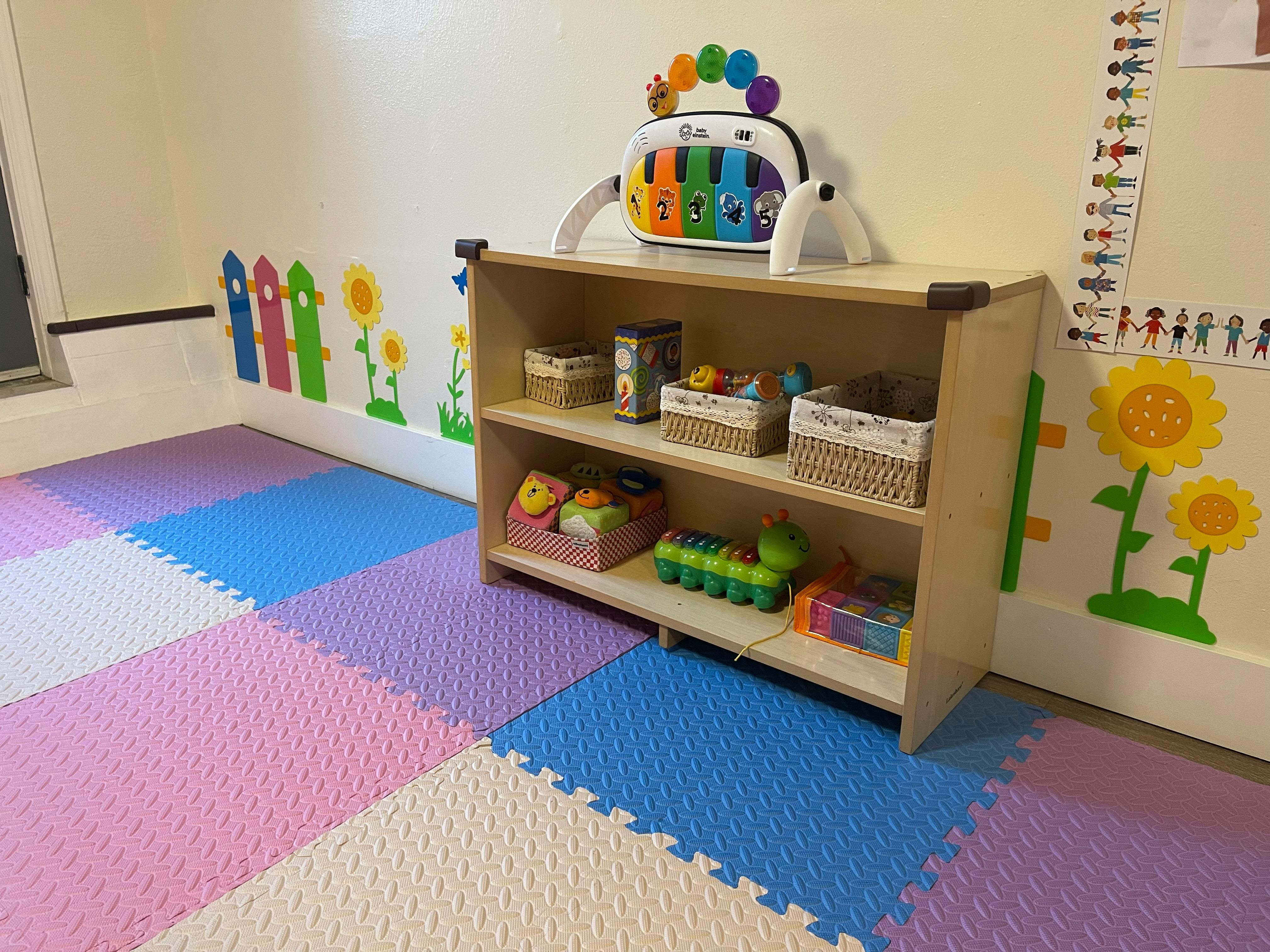 Playroom with colorful floor mats and a wooden shelf with toys