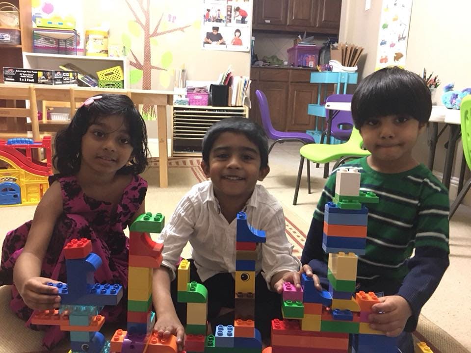 Three children playing with colorful building blocks