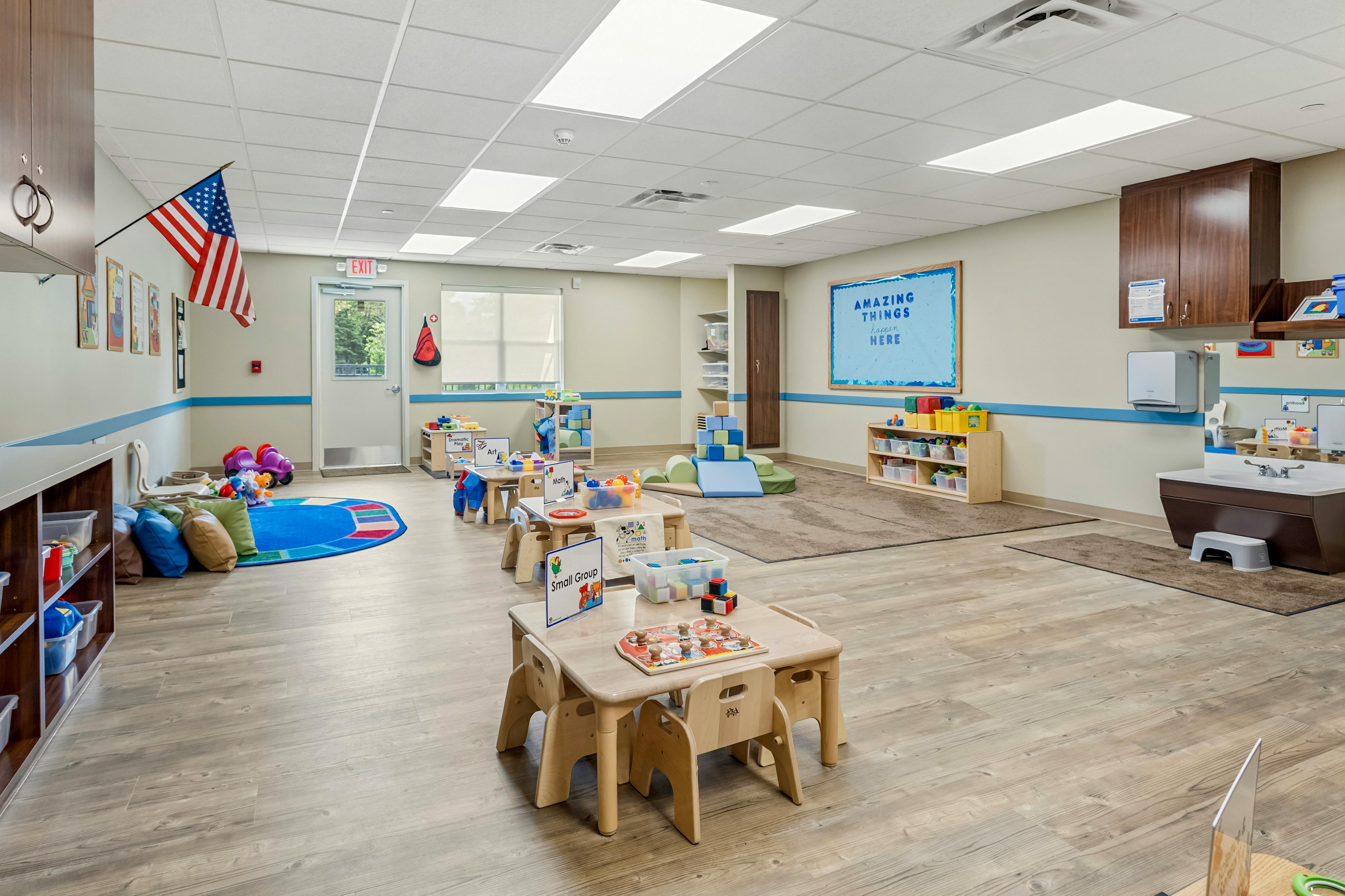 A colorful childcare classroom with small tables and a play sink
