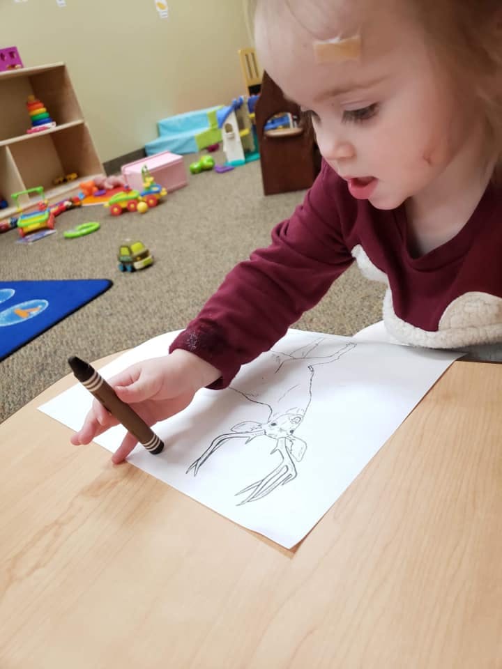Child drawing on paper with a crayon