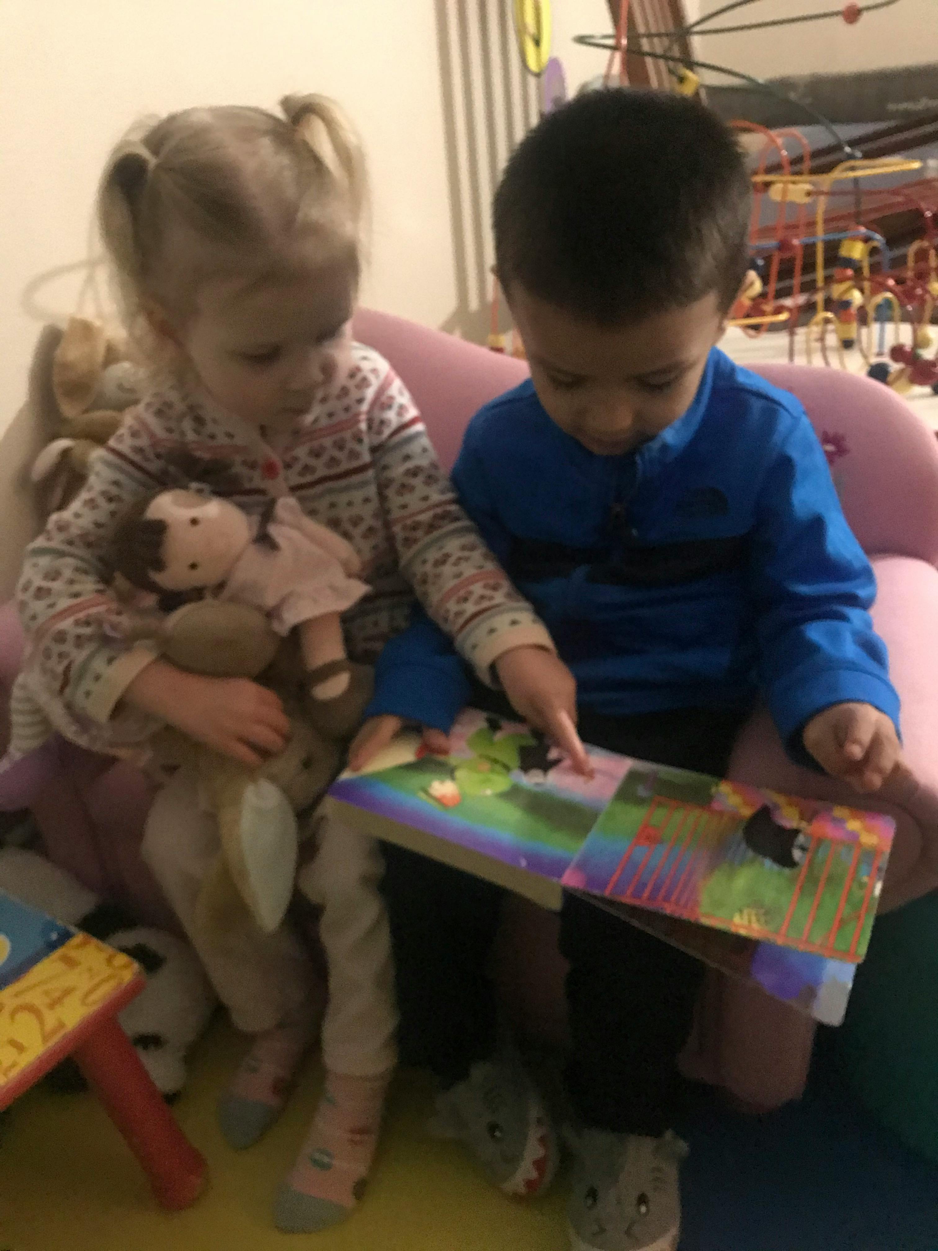 Two children sitting together and looking at a book