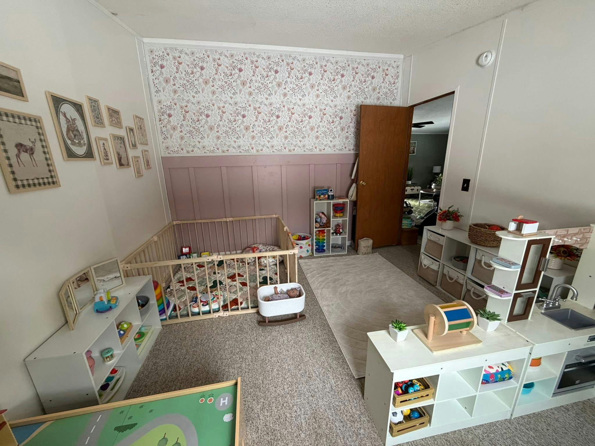 Playroom with a wooden playpen, toy storage shelves, and a toy kitchen