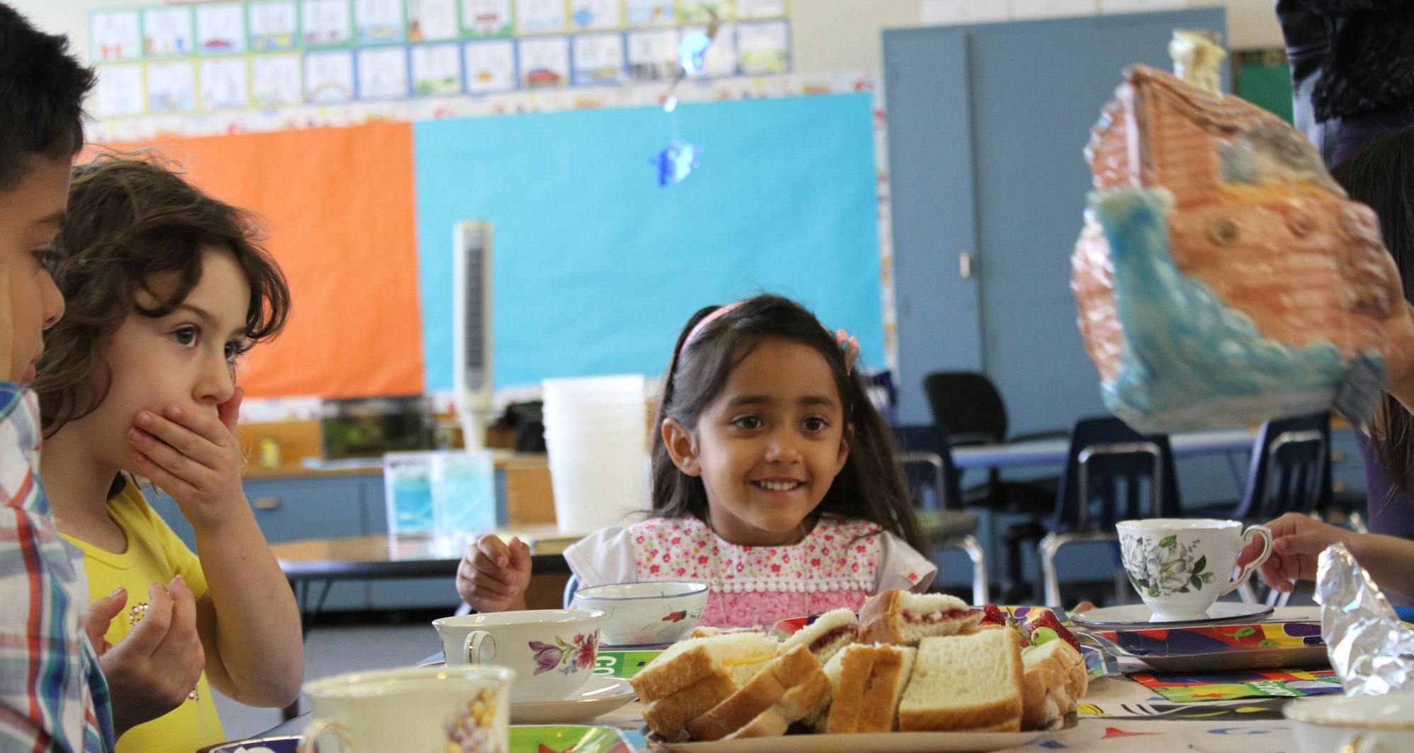 Children at a table with sandwiches and cups