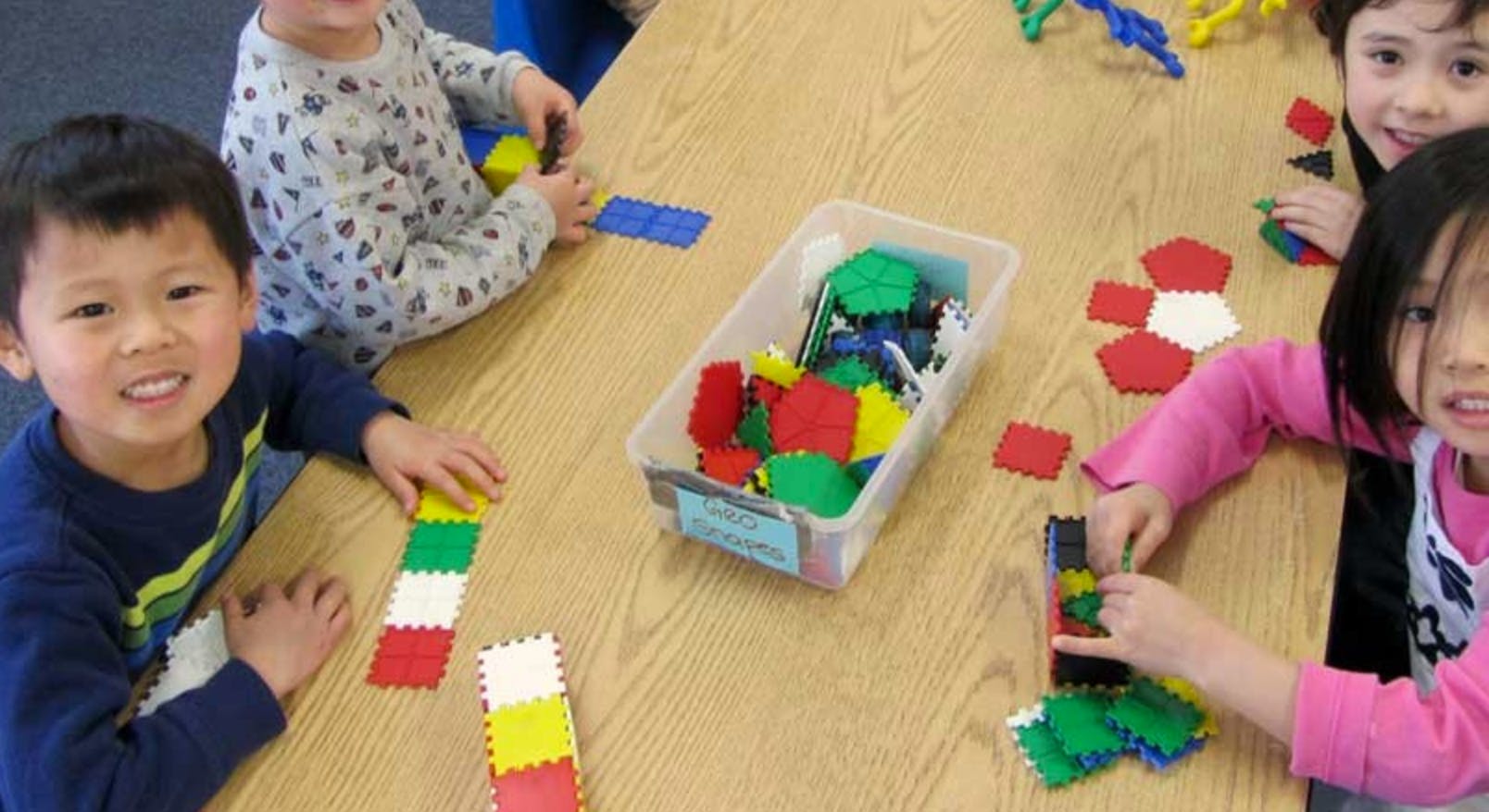 Children playing with colorful interlocking blocks at a table