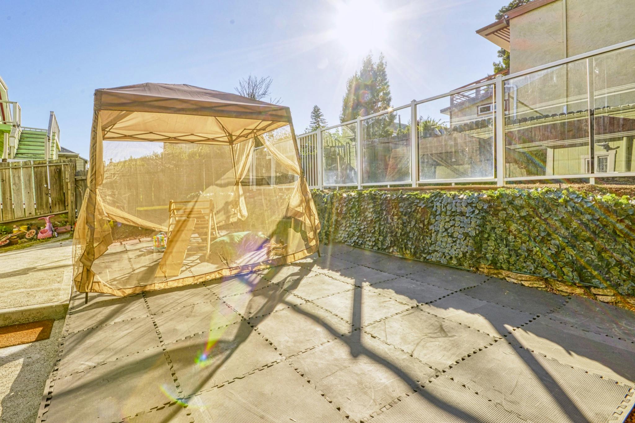Outdoor patio with a gazebo and a fence covered in greenery