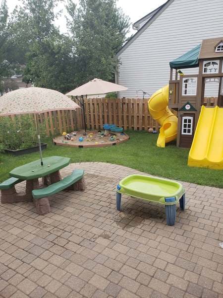 Backyard with a play structure, sandbox, and patio furniture