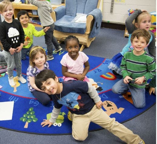 Group of children on a colorful rug in a classroom