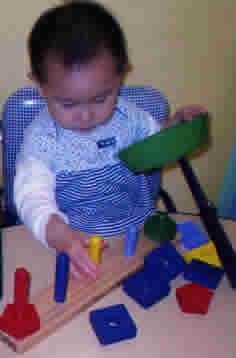 Child playing with colorful wooden blocks and shapes on a wooden board