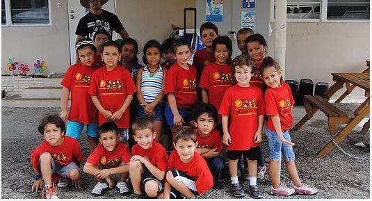 Group of children and one adult posing outdoors