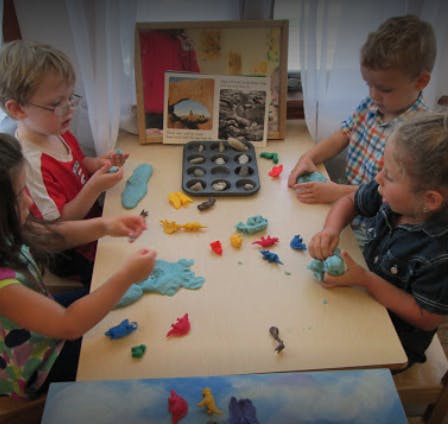 Four children playing with modeling clay at a table