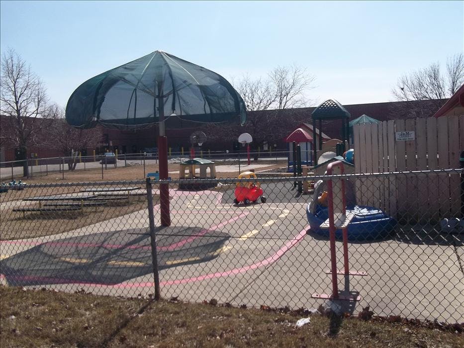 A fenced empty playground with a large umbrella structure and play equipment