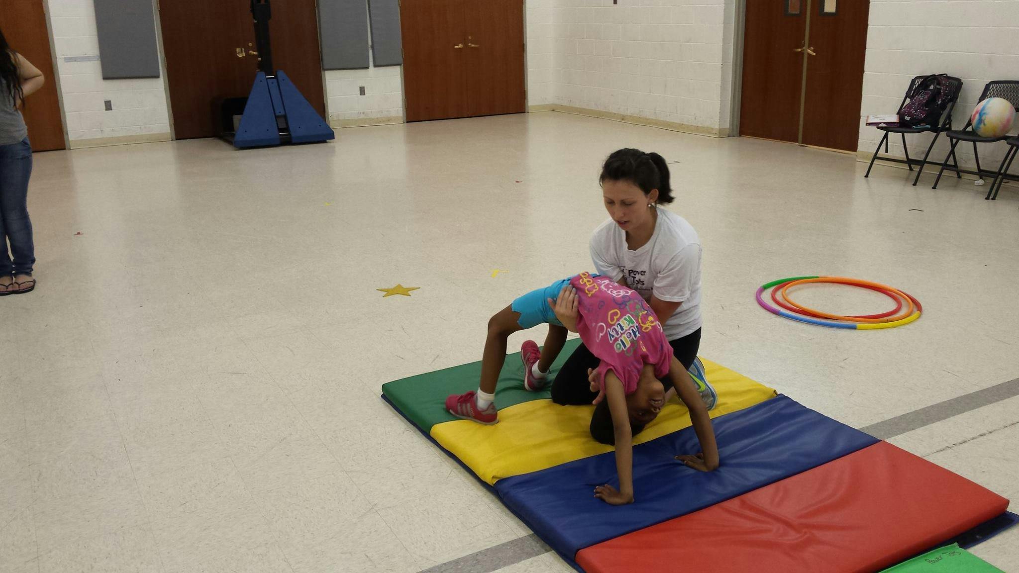 Person assisting child in a backbend on a mat