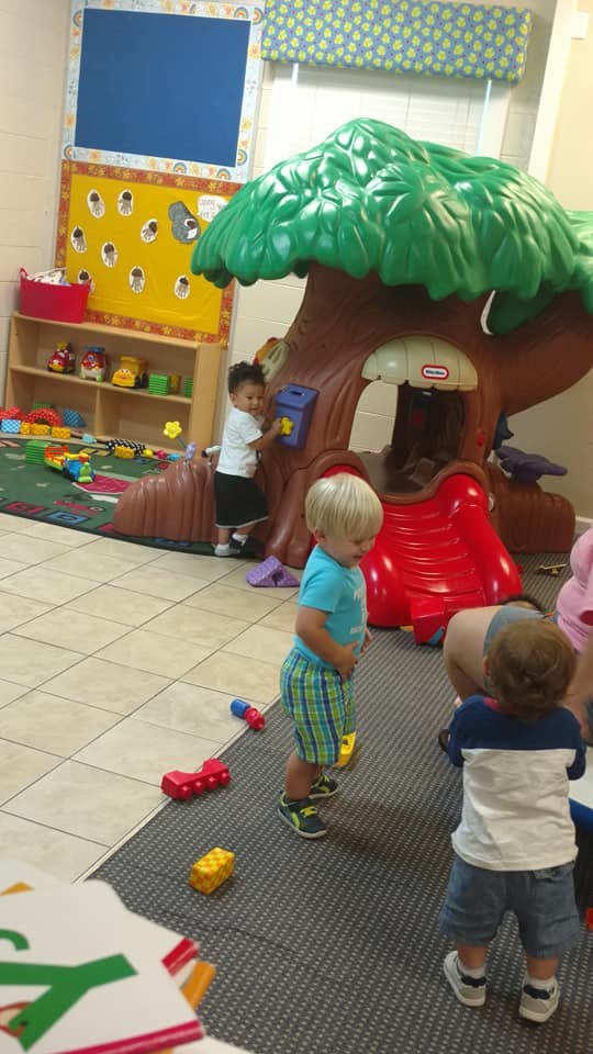 Children playing in a room with a tree-shaped play structure