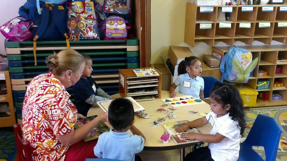 Adult and three children at a table in a classroom