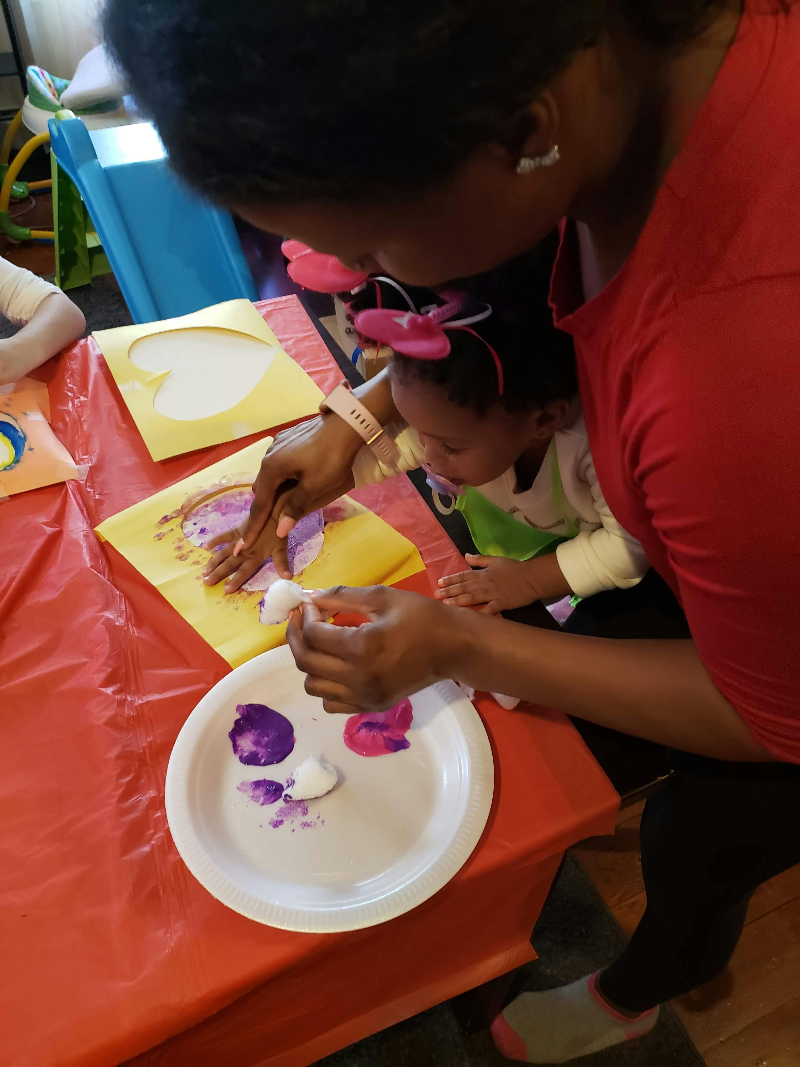 Person and child doing an art project with paint and cotton balls