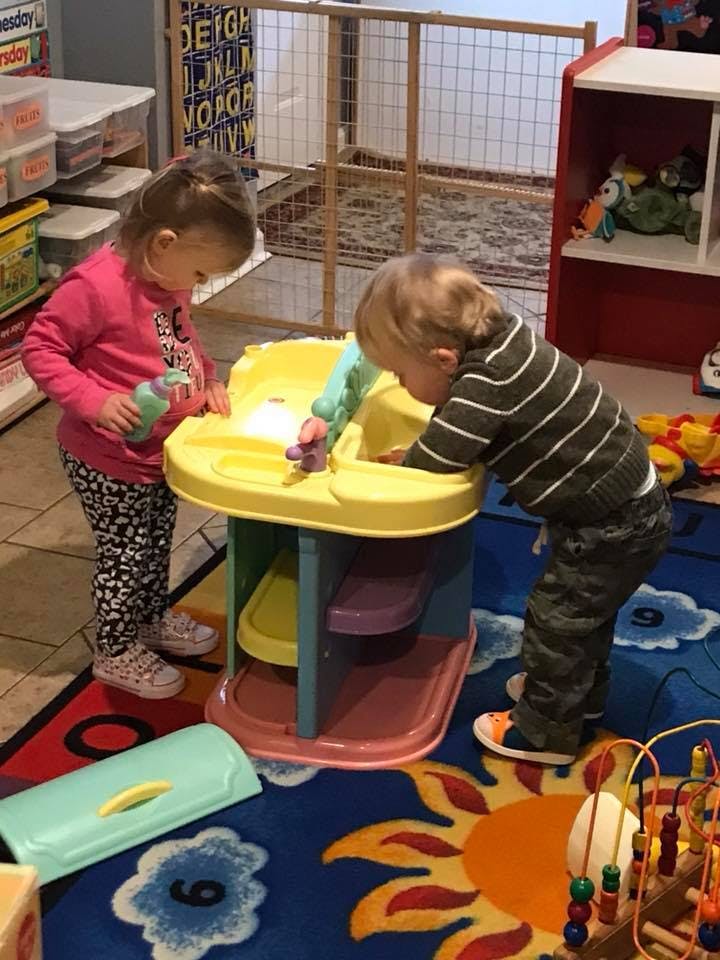 Two children playing with a toy sink