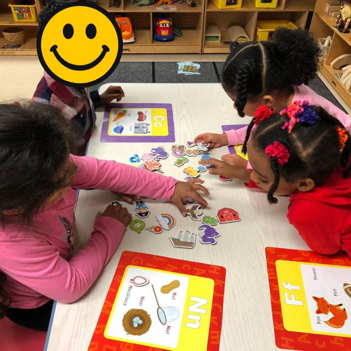 Children playing with learning cards and puzzle pieces at a table
