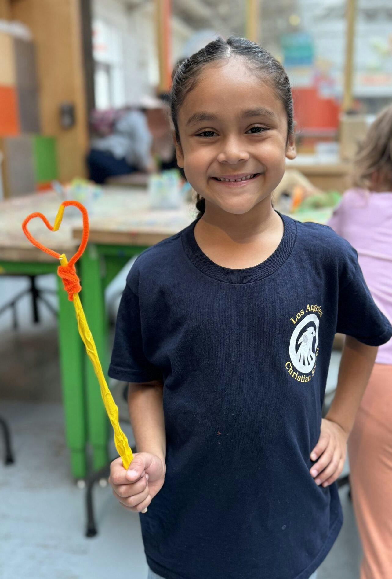 Child in a black shirt holding a handmade heart-shaped wand