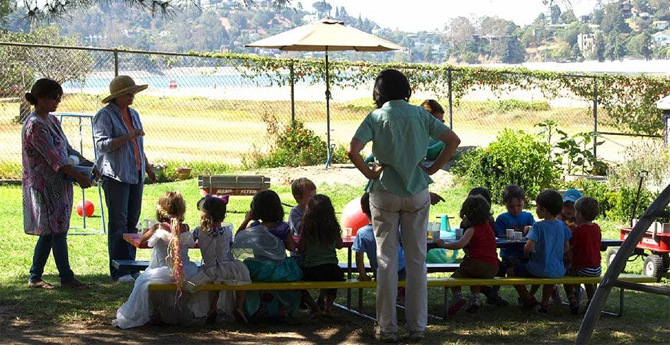 Adults supervising children seated at a table outdoors