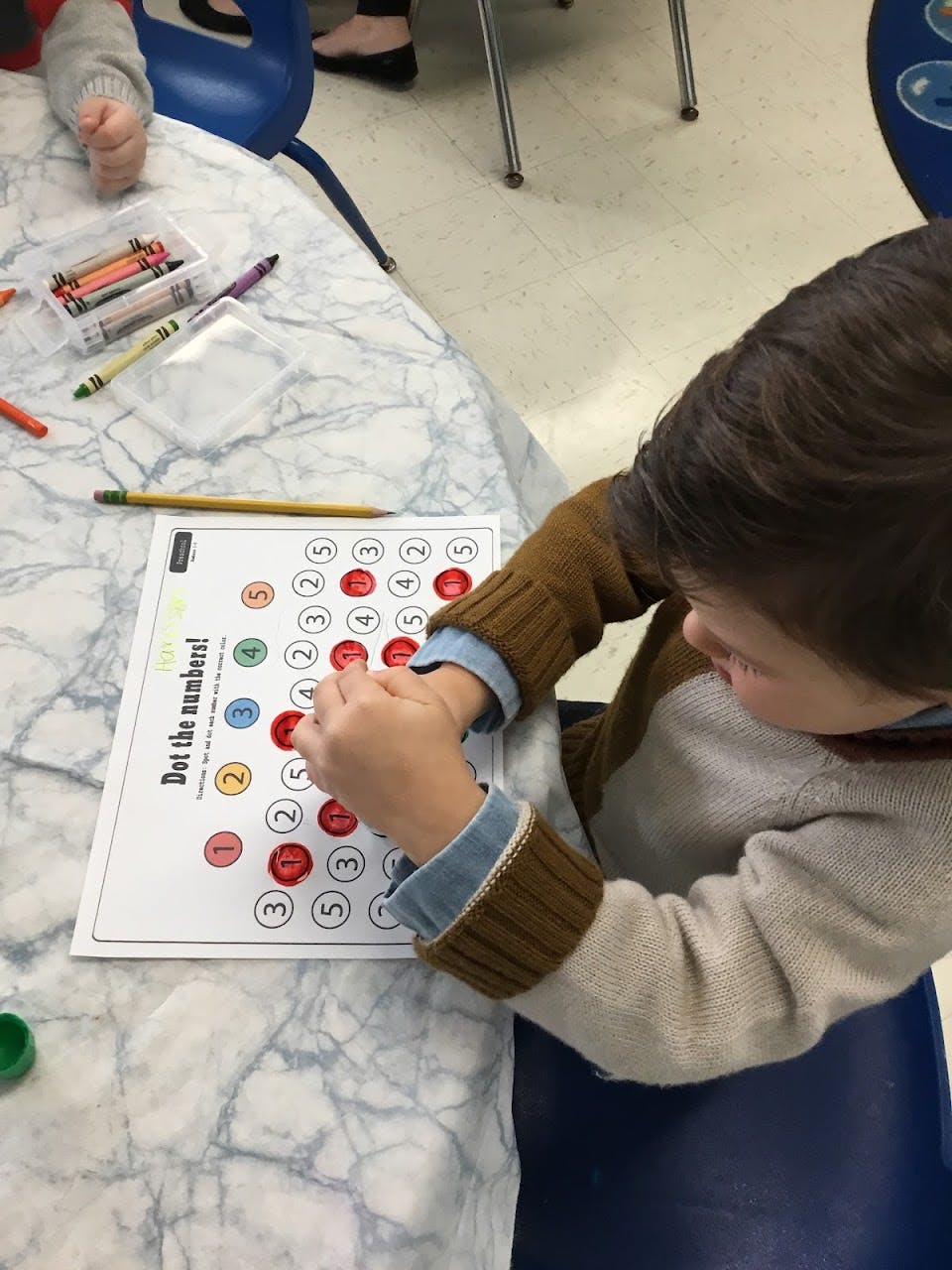 Child working on a number-dotting activity sheet
